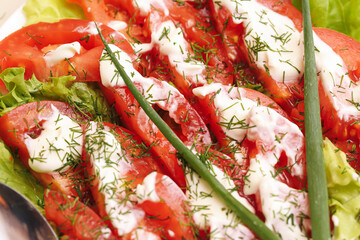 Plakat Fresh tomato salad with creamy dressing dill lettuce and green onion. Red vegetable slices on serving plate healthy appetizer summer meal vegetarian cuisine garden produce and food background.