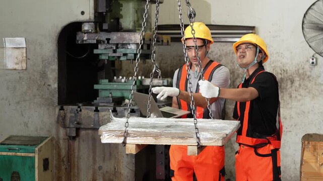 Paused sheet metal inspection waits while the overhead crane carries a wrapped steel bundle across the press shop floor