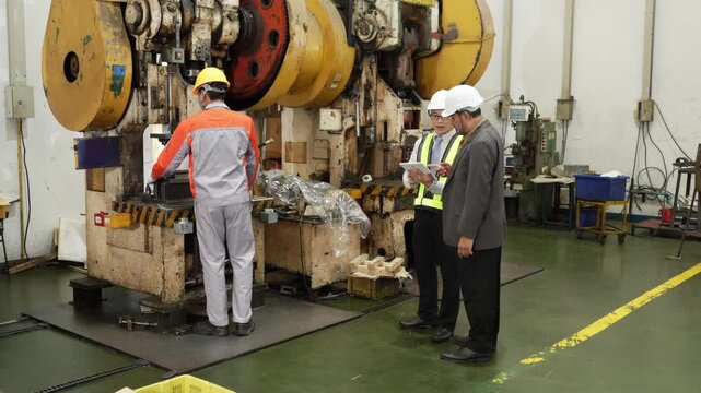 Audit visitors follow the factory operator's hand as he points through the whole stamping sequence in their safety gear