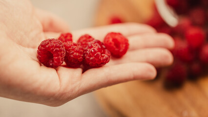Fresh ripe red raspberries held in hand, close up macro shot of organic sweet summer berries © Jakub