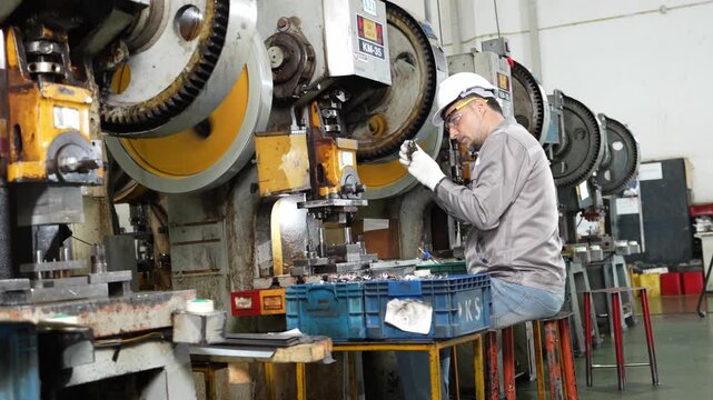 Press stamping holds its rhythm while the operator feeds every blank into the tooling die by hand from the crate