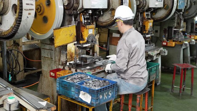 Output of press stamping builds in the crate as the operator clears every finished part away with a pair of tongs