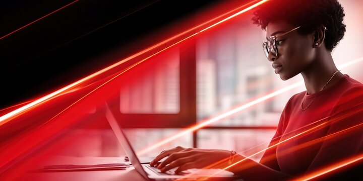 Focused woman in glasses working on laptop with dynamic red light streaks