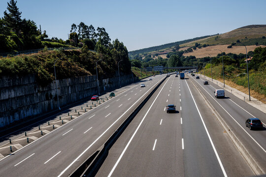 View of a busy highway with vehicles and greenery in the background during a sunny day