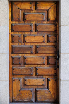 Wooden door with geometric design and metal accents in stone wall