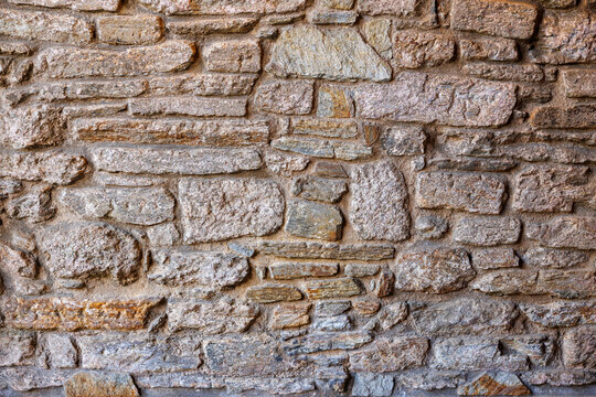 Textured stone wall with varying shades and sizes of stones arranged in a natural pattern