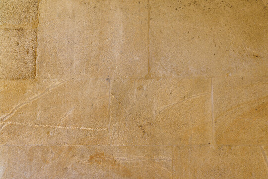 Textured beige stone wall with rough surface and natural patterns