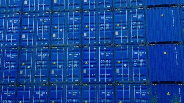 Blue shipping containers stacked at an industrial cargo port