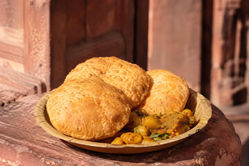 Naklejka premium Agra-style bedhai, crisp urad-dal stuffed fried bread with intensely spiced potato curry, presented on a simple pressed leaf plate instead of luxury tableware
