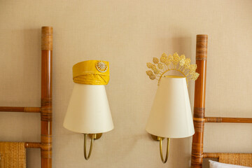 Traditional yellow Malay headress tanjak and gold bridal tiara crown displayed creatively over bedside wall lamps. © udeyismail