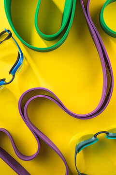 Set of sports swim  accessories, fitness bands on yellow background top view.