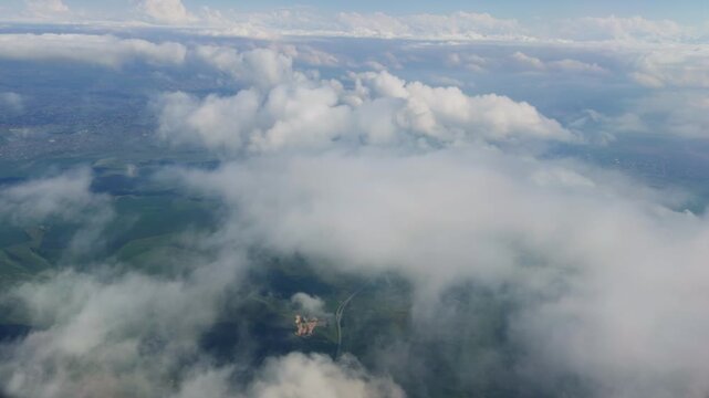 Flying through white clouds above green landscape