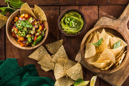 A plate of delicious tortilla nachos  jalapeno peppers, red salsa and guacamole dip.
