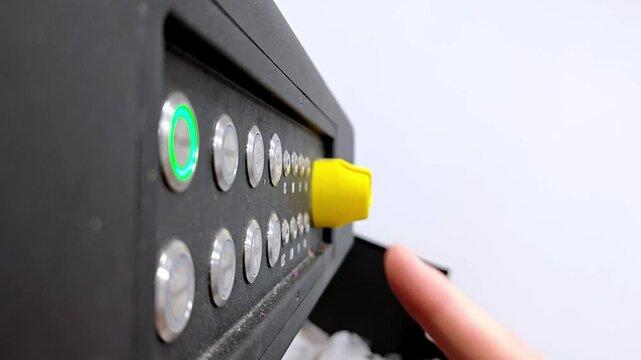 Close-up of a hand pressing power buttons on an industrial control panel, initiating equipment operation.