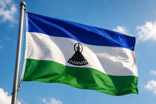 Lesotho National Flag Waving Against a Clear Blue Sky with Flagpole and White Clouds