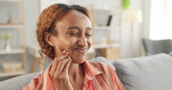 Woman feels toothache pain while touching cheek. Mature woman sits at home with closed eyes, showing dental discomfort and oral sensitivity. A relatable healthcare discomfort concept at home.