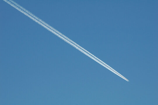 Jet airplane with contrails in clear sky