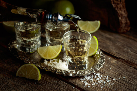 Tequila with salt and lime slices on a silver tray.
