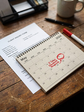 Calendar with Circled Deadline Date beside Inquiry Form on Office Desk
