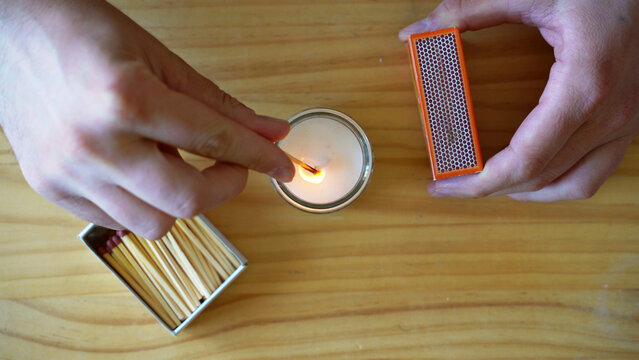 Top view of hands lighting up candle with match