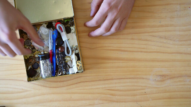 Vintage labours concept. Top view shot of Hands going through Sewing Kit in old metal box
