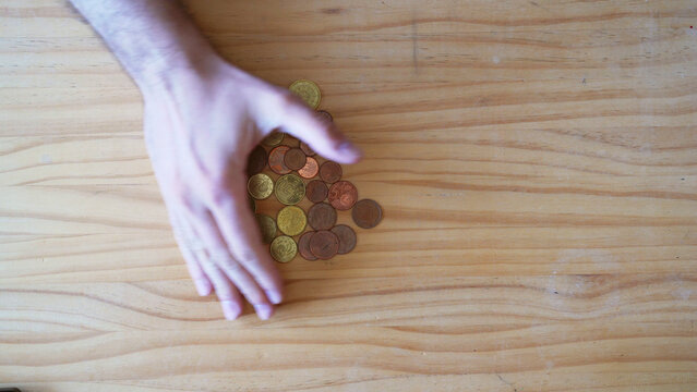 Cash and physical money concept. Stealing and hoarding. Savings. Hand grabbing Coins onver wooden table