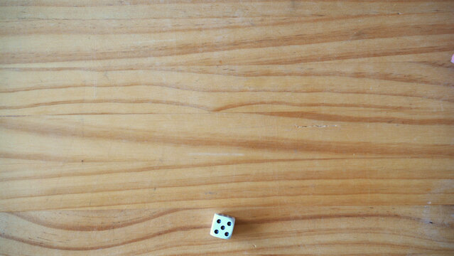 Luck and gambling concept. Dice with number five over wooden table