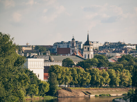 Riverside view of historic churches and greenery along the water's edge in Vilnius