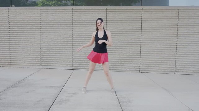 Energetic young woman dancing outdoors in slow motion
