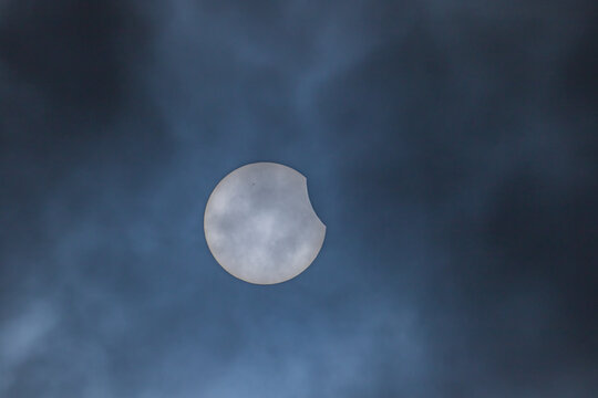 Partial solar eclipse viewed through dark dramatic clouds in Diyarbakir, Turkey.