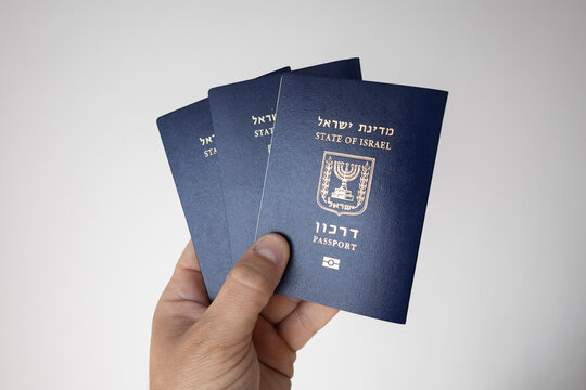 Hand holding multiple Israeli passports (Darkon) on a neutral background
