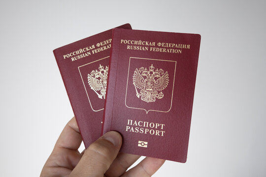 Hand holding two Russian passports on a neutral background