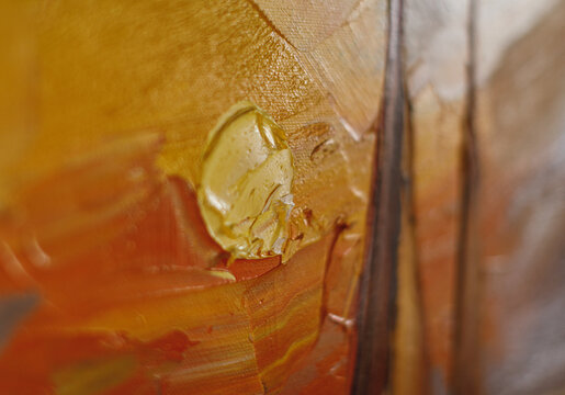 Abstract macro texture of layered oil paint in warm orange and yellow tones with selective focus and visible brushwork. Artistic background for creative design concepts.