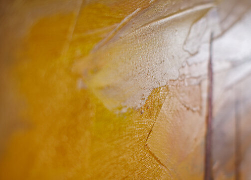 Macro view of layered yellow and golden oil paint with visible brush marks and selective focus. Abstract artistic surface suitable for creative backgrounds and design projects.