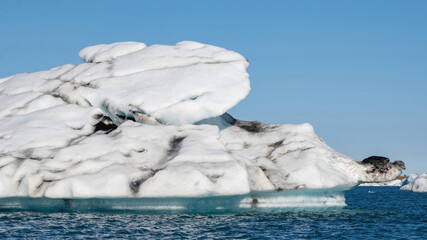 Beautiful ice fragments from Vatnajokull glacier drifting across Jokulsarlon lagoon before reaching the sea during summer in Iceland, creating striking natural shapes. © Asanee
