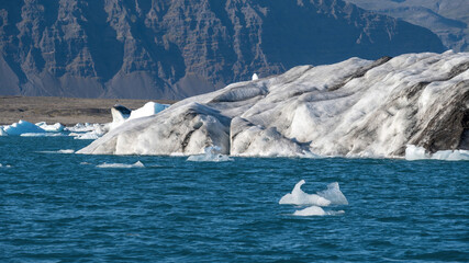 Beautiful ice fragments from Vatnajokull glacier drifting across Jokulsarlon lagoon before reaching the sea during summer in Iceland, creating striking natural shapes. © Asanee