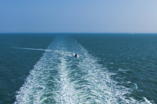small motorboat traveling wide white water wake left behind large ship
