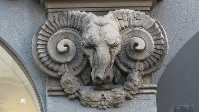 Architectural stone relief of a ram head sculpture on a building facade