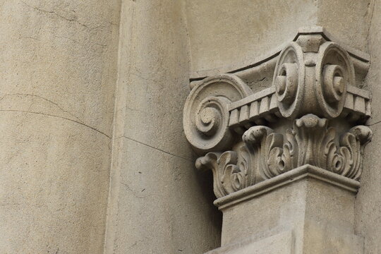 Composite ionic column capital with ornamental volutes on historic building facade