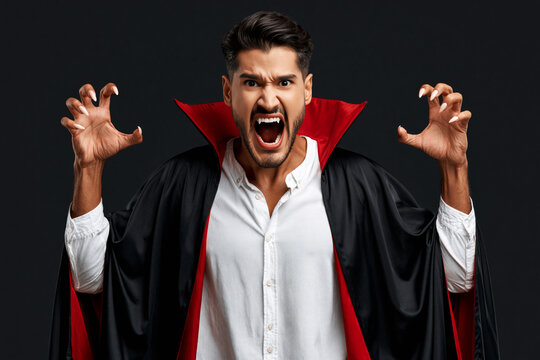 Screaming man in black and red vampire cape with claw pose, Halloween spooky concept