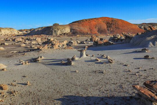 Beautiful scenic view of a red sandstone hill with unique natural hoodoo rock formations in desert at sunset