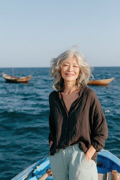 Smiling older woman on a blue boat at sea background for travel banner and seaside lifestyle wallpaper
