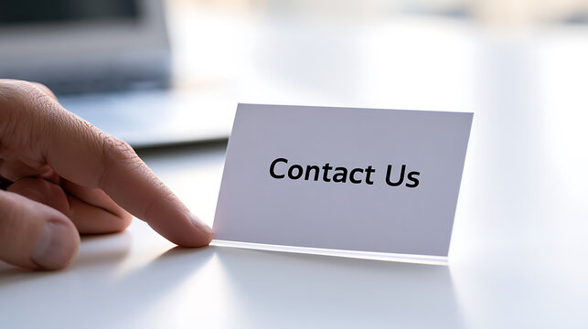 Business person hand point at contact us message on a paper card desk setup professional corporate customer service support communication