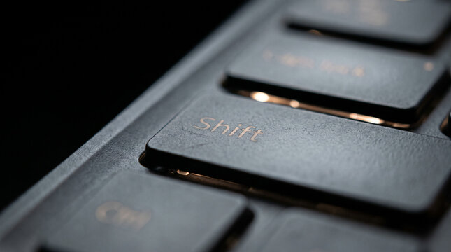 Macro close up of Shift key on backlit computer keyboard with copy space for business change concept