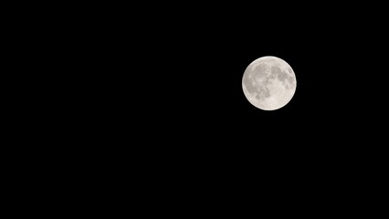 Astronomy photography of a bright glowing full moon isolated on a black background © DziaDzia