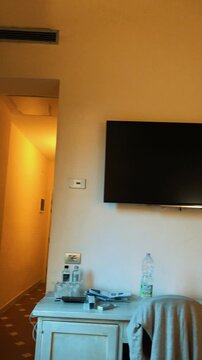 Interior pan of a cozy vintage hotel room featuring classic wooden furniture, a gilded antique mirror, flat screen television, and hallway entrance in an authentic European boutique hotel.

