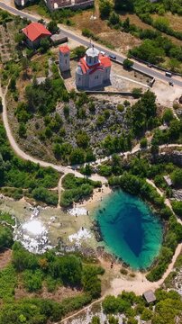 Aerial view of the Cetina River spring, known as the Eye of the Earth, with a nearby church in Croatia