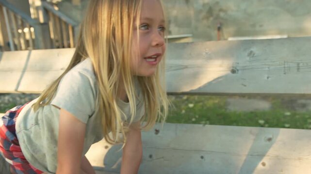 Boy sitting on wooden porch steps talking and smiling in warm golden light