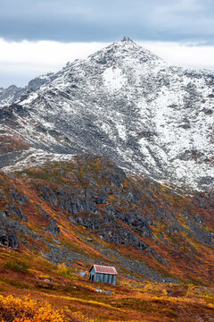 Shack sitting below autumn tundra mountain peak