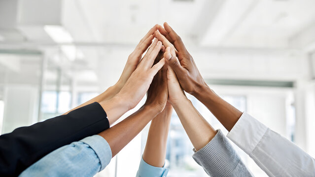 Business team raising hands in a group high five represents collaboration shared motivation workplace unity and collective success.